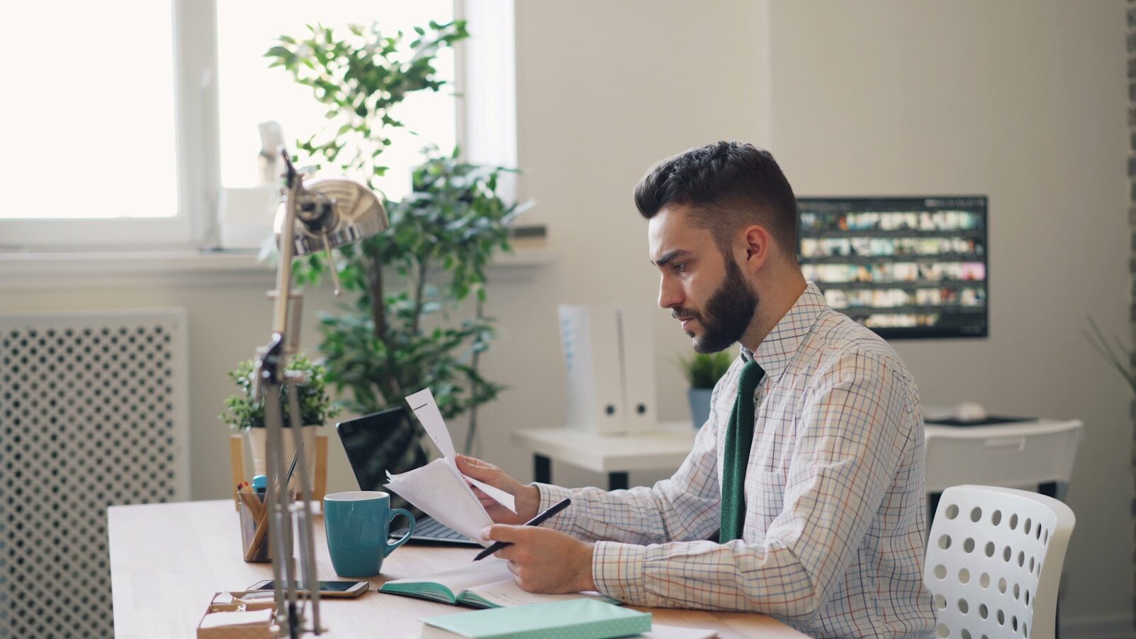 a man sitting at a desk with a laptop and papers relacionada a Processo administrativo parado: o que verificar primeiro