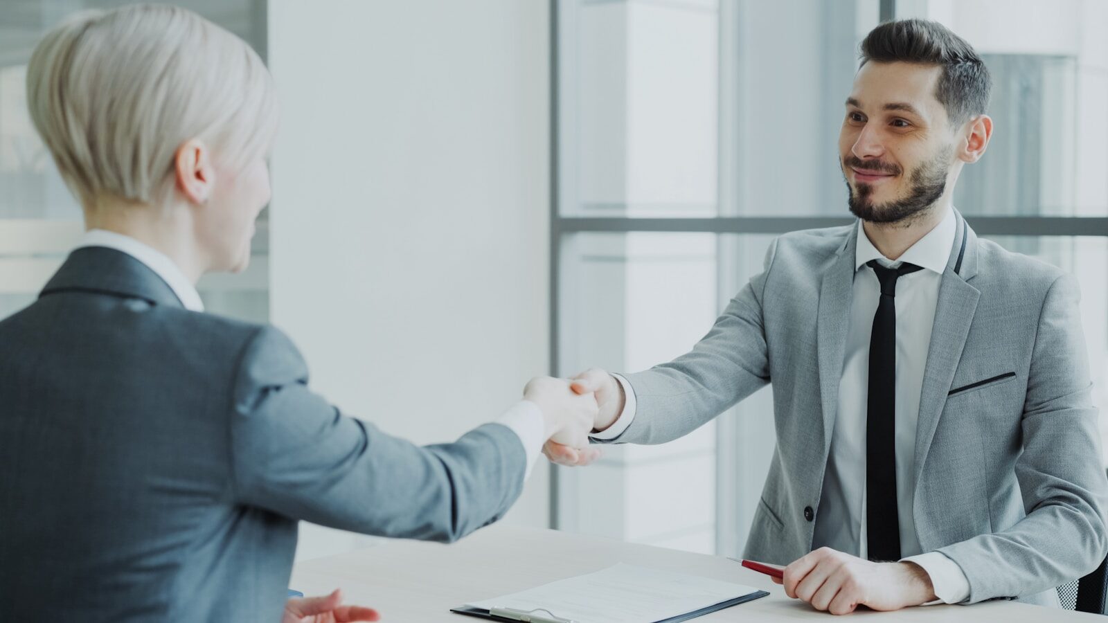 Two professionals shaking hands across a table. relacionada a Advogado de INSS online é seguro?