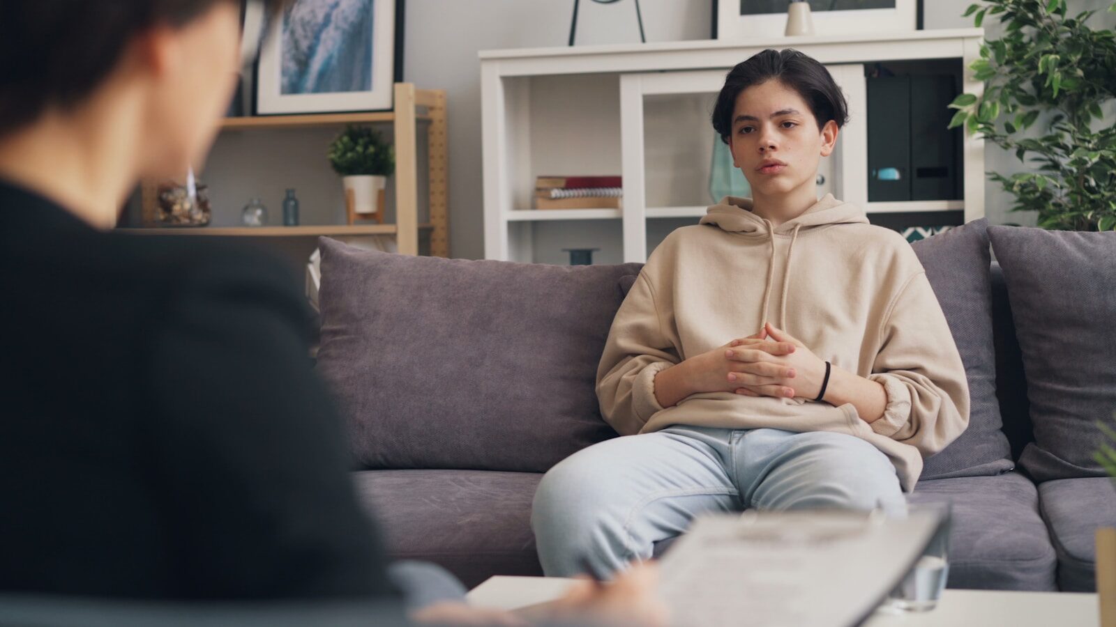 a woman sitting on a couch in a living room relacionada a Como saber se seu caso de INSS precisa de advogado