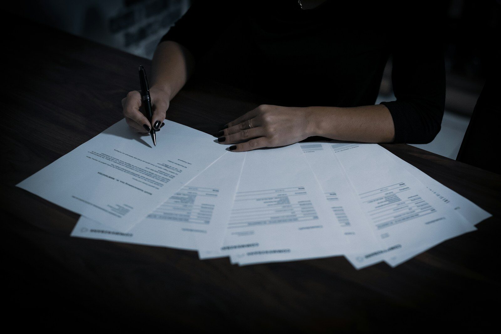 a woman sitting at a table with lots of papers relacionada a Período de graça: quanto tempo você continua protegido pelo INSS